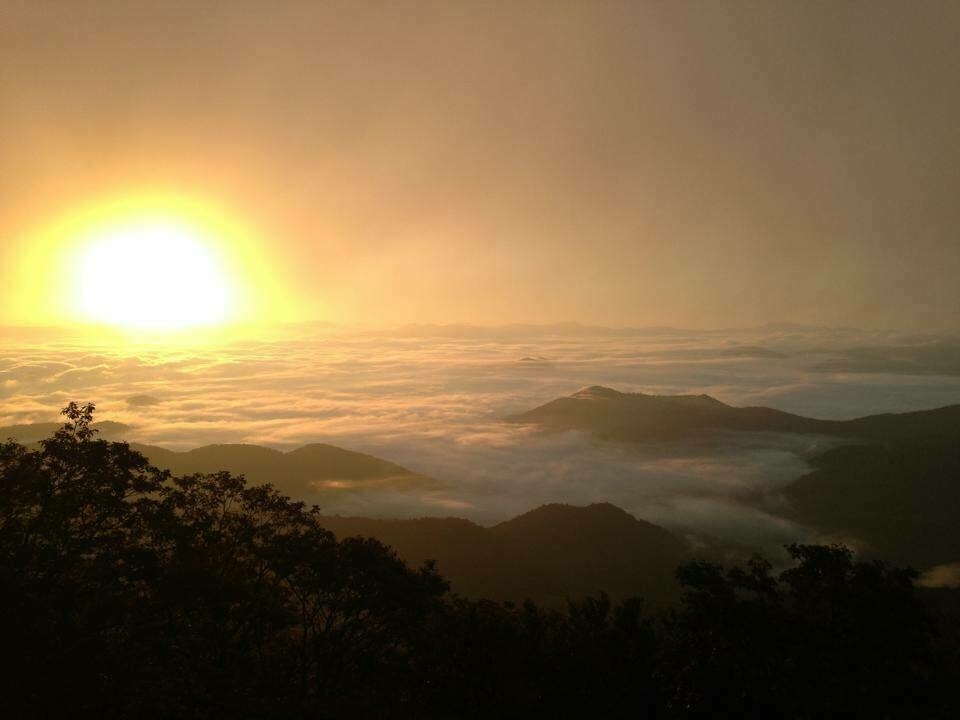 Sunrise seen from a mountain top with cluds in the valley below