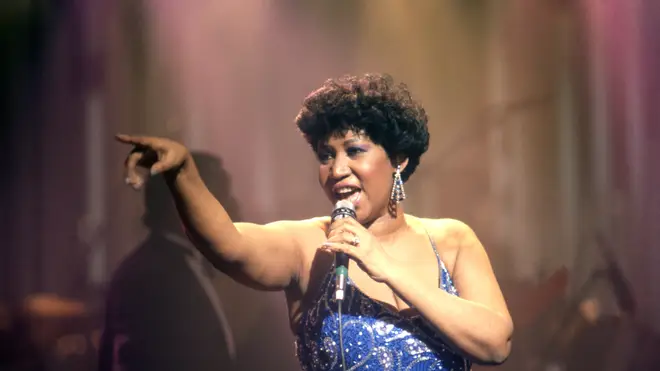 Aretha Franklin in middle age, wearing a blue dress and singing