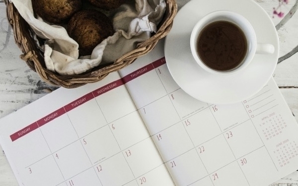 a cup of coffee sitting on an open paper day planner