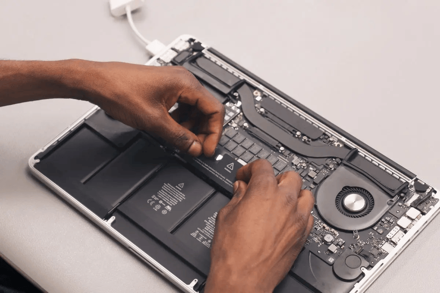 A computer technician’s hand working on a laptop