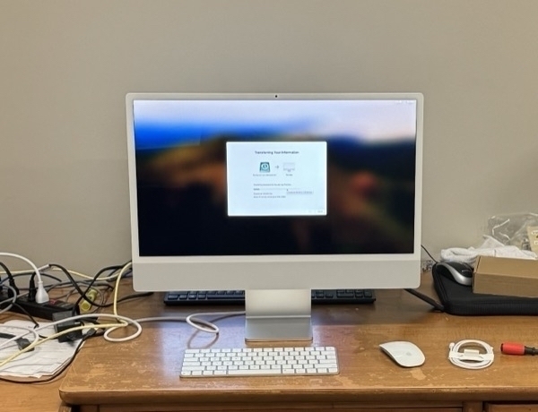 A white M3 iMac with migration assistent on the screen sitting on a wooden desk
