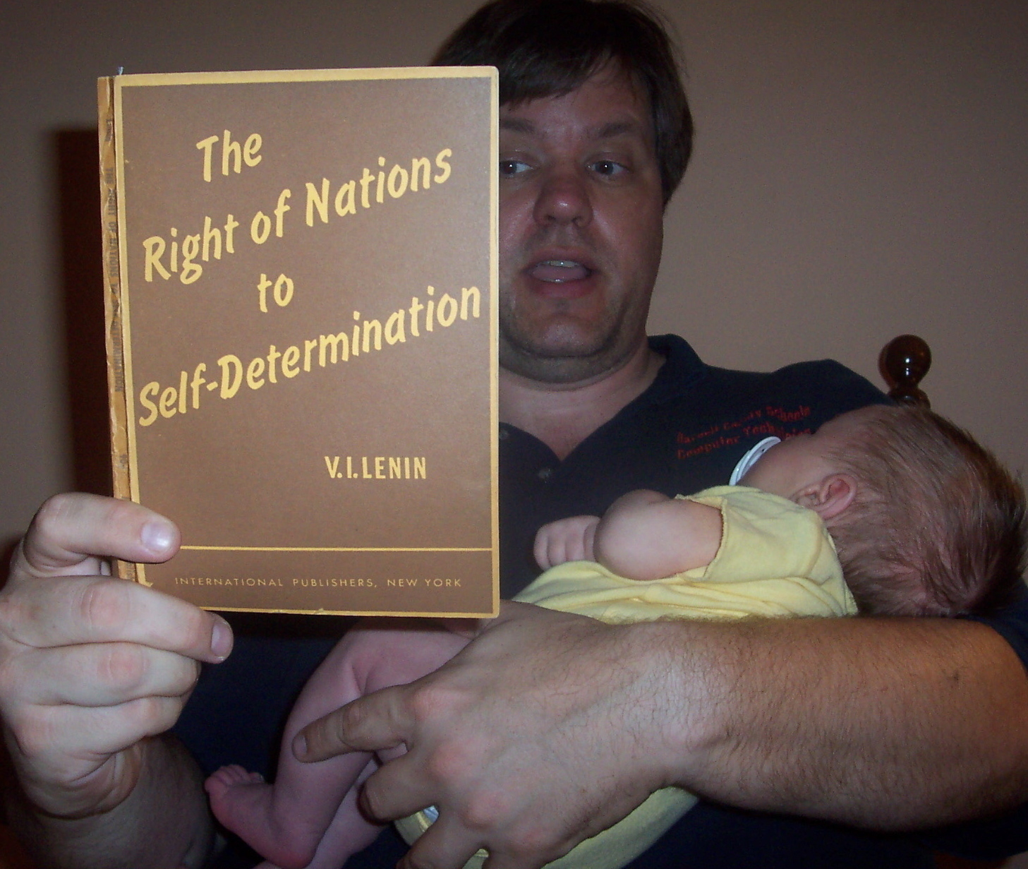 A man reading a book by Lenin to a baby