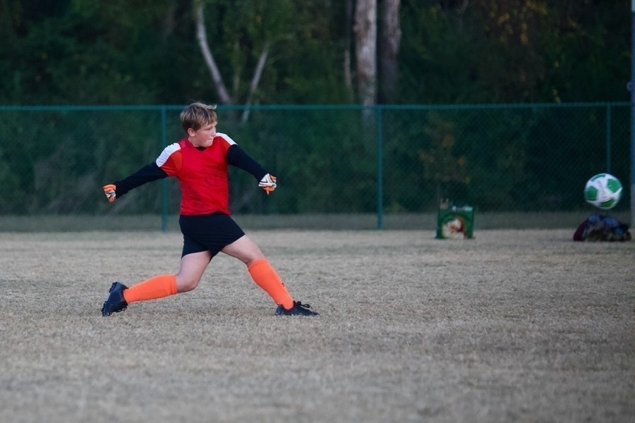 A youth soccer player kicking the ball