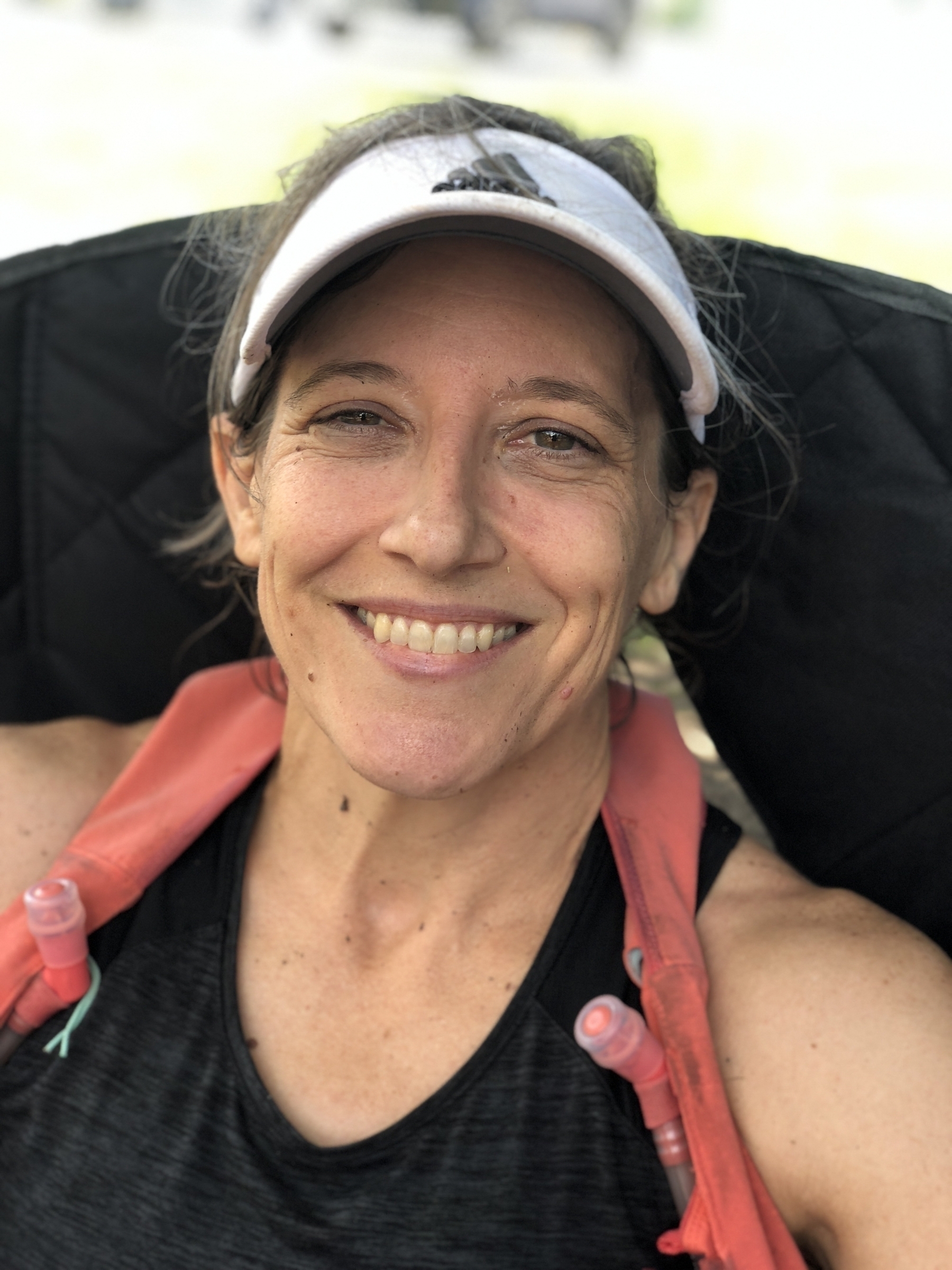 A beautiful woman smiling and wearing a visor after running 30 miles on the Appalachian Trail