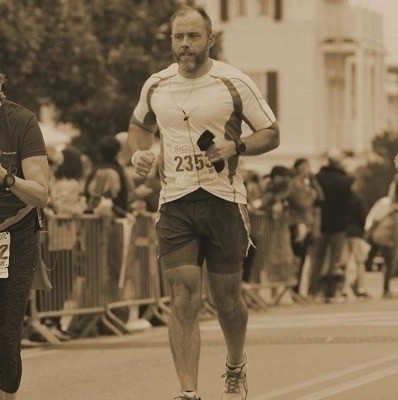 A fit man running a race with a number bib on