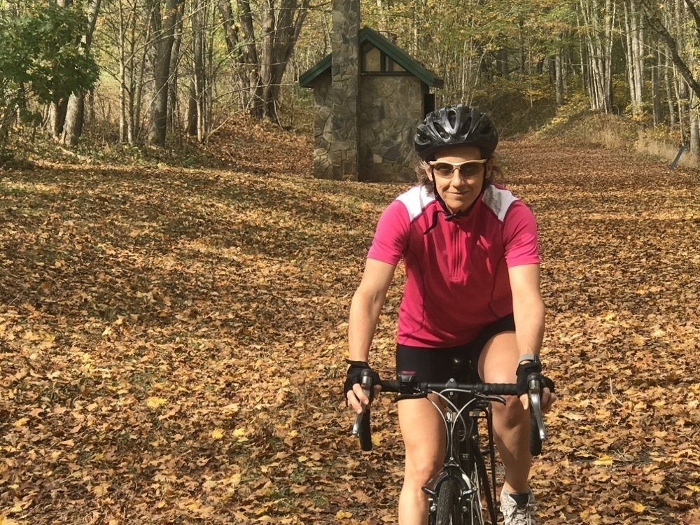 A woman on a bicycle on a wooded path in the autumn