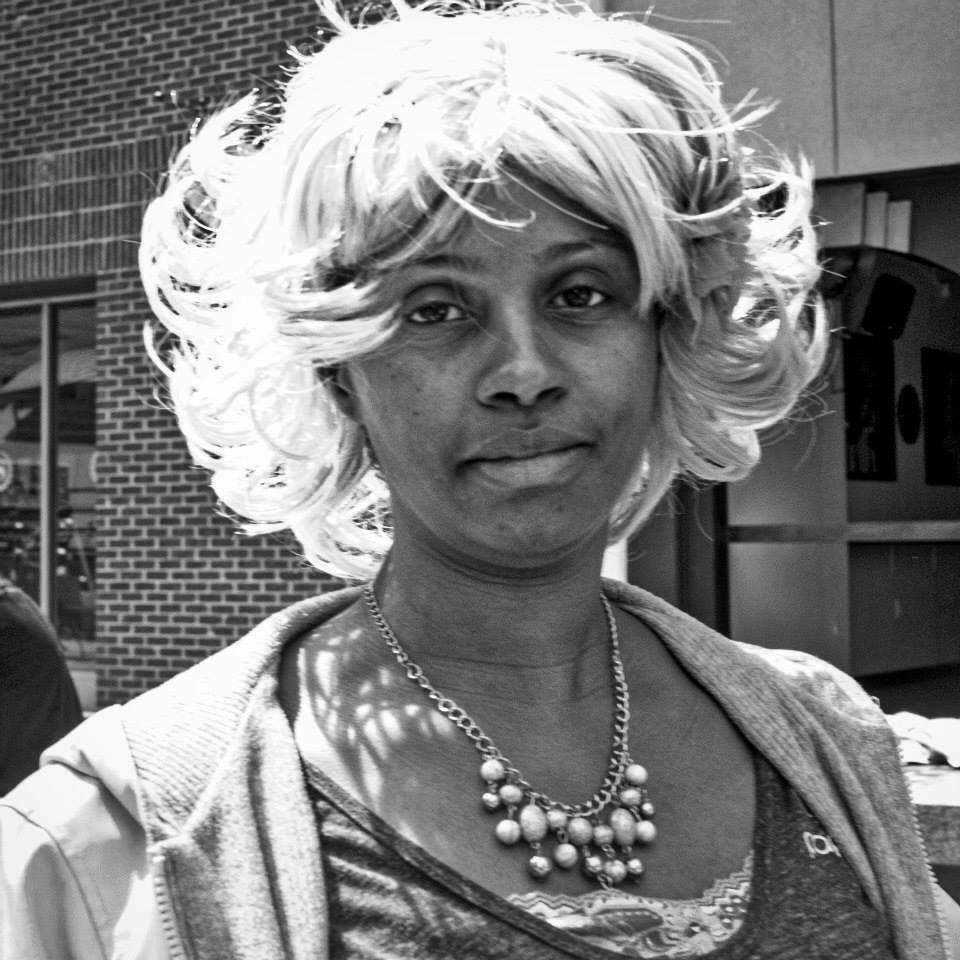 A black and white photo of a woman wearing a light-colored wig
